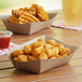 A table with two Southern Champion paper food trays filled with fried chicken and fries.