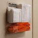 A Quick Dam wall-mounted dispenser holding white and orange towels.