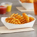 A Southern Champion white paper food tray with a basket of french fries and a dipping sauce.
