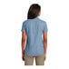 A woman wearing a Port & Company faded blue short sleeve denim button-down shirt.