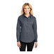 A woman wearing a Port Authority steel gray and light stone long sleeve poplin shirt.