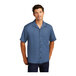 A man wearing a blue Port Authority short sleeve camp shirt.