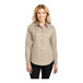 A woman wearing a tan Port Authority long sleeve dress shirt.
