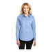 A woman wearing a light blue Port Authority long sleeve button-up shirt.