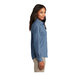 A woman wearing a faded blue Port & Company short sleeve denim button-down shirt.