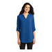 A woman wearing a Port Authority blue short sleeve blouse.