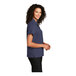 A woman wearing a Port Authority navy blue performance staff shirt.