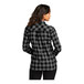 A woman wearing a gray and black buffalo check flannel shirt.