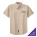 A close-up of a tan Port Authority short sleeve dress shirt with a logo on the chest.