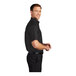 A man in a black and light stone Port Authority short sleeve dress shirt.
