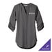 A Port Authority sterling gray women's tunic blouse with white custom text on the counter.