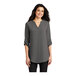 A woman wearing a Port Authority sterling grey short sleeve blouse.