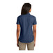 A woman wearing a Port & Company ink blue short sleeve denim button-down shirt.