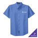 A Port Authority ultramarine blue short sleeve dress shirt on a counter with a logo on the chest.