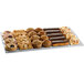 A Tablecraft natural rectangular platter on a counter in a bakery display with pastries and muffins on it.