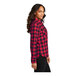 A woman wearing a red and black plaid Port Authority flannel shirt.