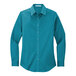 A teal green Port Authority women's long sleeve dress shirt with white buttons.