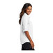 A close-up of a woman wearing a white Port Authority short sleeve shirt.