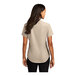 A woman wearing a beige Port Authority short sleeve dress shirt.