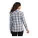 A woman wearing a gray and white plaid Port Authority flannel shirt.