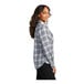 A woman wearing a Port Authority gray and cream plaid flannel shirt.