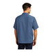 A man wearing a blue Port Authority camp shirt with short sleeves.