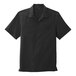 A black Port Authority short sleeve staff shirt with a collar and a pocket on a counter.