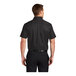 A man wearing a Port Authority black and light stone short sleeve dress shirt.