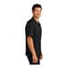 A man wearing a black Port Authority short sleeve camp shirt.