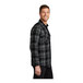 A man wearing a gray and black plaid flannel shirt.