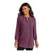 A woman wearing a purple Port Authority short sleeve blouse with a v-neck.