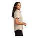 A woman smiling in a tan Port Authority short sleeve dress shirt.