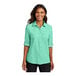 A woman wearing a bright seafoam Port Authority short sleeve shirt.