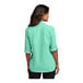 A woman wearing a bright seafoam Port Authority short sleeve shirt.