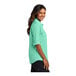 A close-up of a Port Authority bright seafoam short sleeve shirt on a woman.