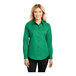A woman wearing a Port Authority court green long sleeve dress shirt.