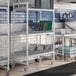 A Cambro Camshelving Premium drying rack cart with trays on white and blue shelves.