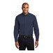 A man wearing a Port Authority navy and light stone long sleeve poplin shirt.