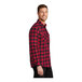 A man wearing a Port Authority red and black buffalo check flannel shirt.