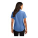 A woman wearing a Port Authority ultramarine blue short sleeve shirt.
