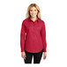 A woman wearing a red Port Authority long sleeve dress shirt.