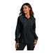 A woman wearing a black Port Authority short sleeve button-down shirt.