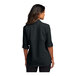 A woman wearing a black Port Authority short sleeve shirt.