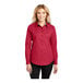 A woman wearing a red Port Authority long sleeve dress shirt.