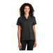 A woman wearing a black Port Authority short sleeve staff shirt.