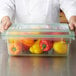 A chef holding a Carlisle green food storage box filled with red and yellow bell peppers.