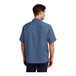 A man wearing a Port Authority blue short sleeve camp shirt.