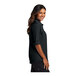 A woman wearing a black Port Authority short sleeve shirt.