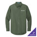 A Port Authority long sleeved green dress shirt on a counter with the company logo.