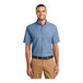 A man wearing a faded blue Port & Company short sleeve denim button-down shirt.